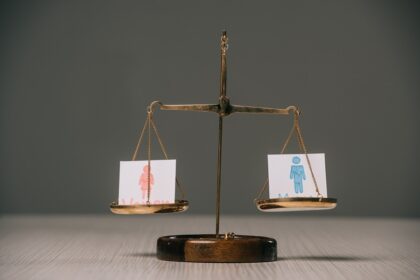 male and female symbols on scales on wooden table on grey, gender equality concept