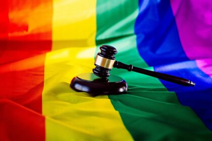 Uganda Woden judge mallet symbol of law and justice with lgbt flag in rainbow colours. Lgbt rights and law